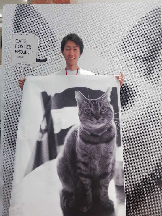 大きな猫ちゃんのポスターを手に、ニンマリ顔のスタッフ